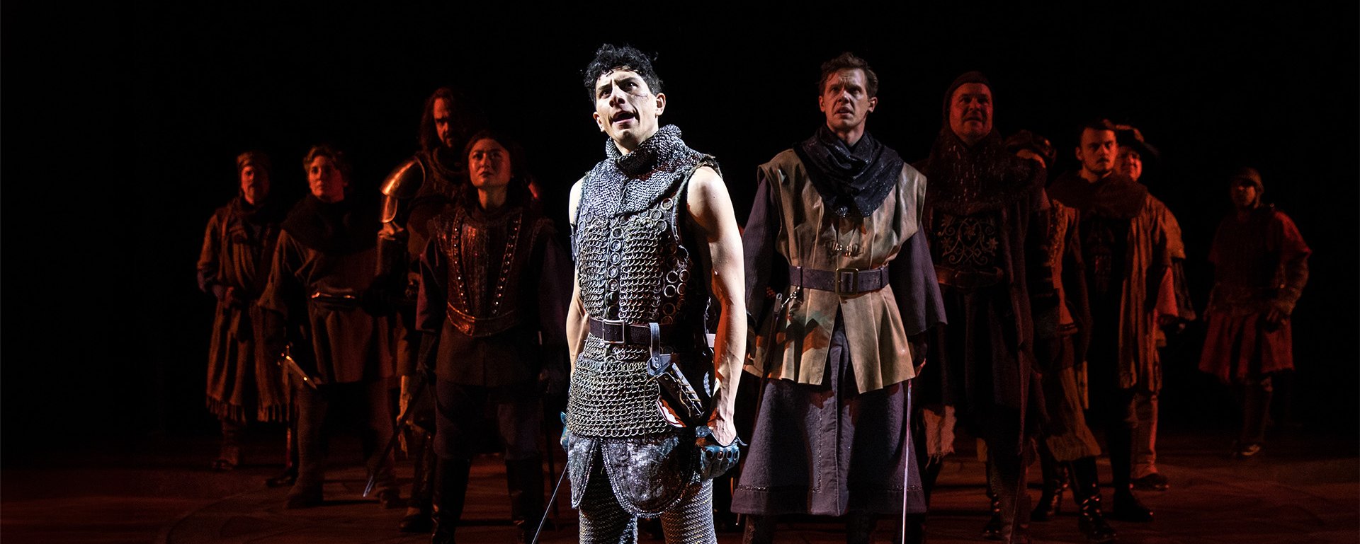 Daniel Molina stands center stage, the company behind him, during a scene from Henry V.